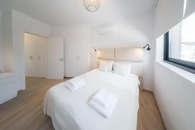 a white bedroom with a large white bed with two pillows at CasaMar - Upscale One-Bedroom Apartment by the Sea in Larnaka