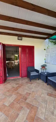 a patio with red doors and benches and a table at Barefoot Beach House in Larnaka