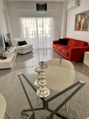 a living room with a glass table and a red couch at Charming 2 Bdr Nicosia Apt Free Parking & Wi-Fi in Nicosia
