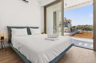 a bedroom with a large white bed and a large window at Azure Sama Villa in Protaras