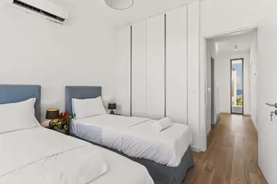 two beds in a room with white walls and wooden floors at Azure Sama Villa in Protaras