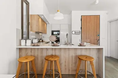 a kitchen with three wooden stools at a counter at Azure Leda Villa in Protaras