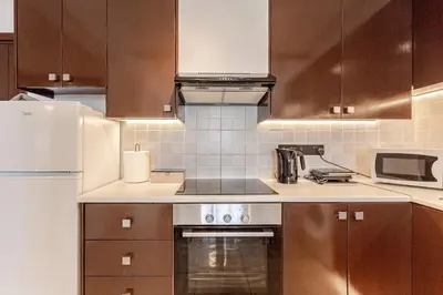 a kitchen with brown cabinets and a stove top oven at Seaside View 1-bedroom apartment! in Larnaka