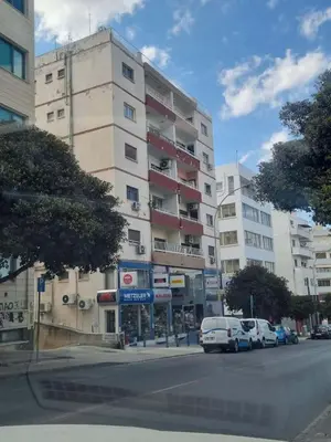 a tall building with cars parked in front of it at Karyatis Building in Nicosia