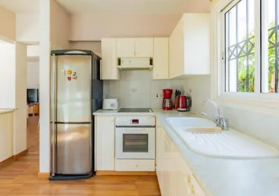 a kitchen with white cabinets and a stainless steel refrigerator at Anemone Seaview Villa DPS01 in Protaras