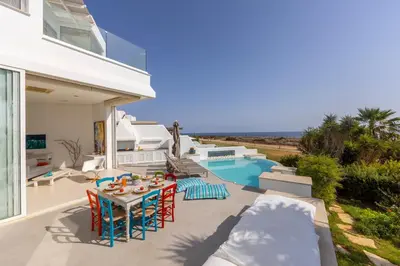 a patio with a table and chairs and a pool at Protaras Seafront Villa AleMar in Protaras