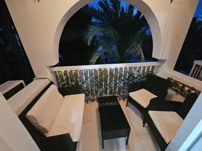 a balcony with chairs and a palm tree at night at D&D Apartment in Paralimni