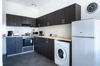 a kitchen with black cabinets and a white refrigerator at Phoenix 2-Bedroom Apartment in Larnaka