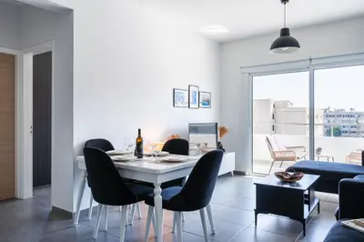 a dining room with a white table and black chairs at Phoenix 2-Bedroom Apartment in Larnaka