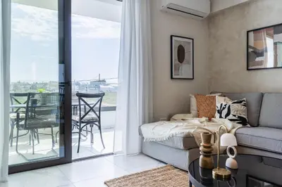 a living room with a couch and a balcony at Vervana 2-Bedroom Apartment in Larnaka
