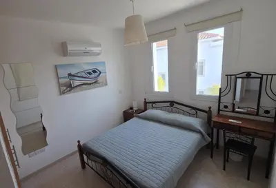 a bedroom with a bed and a desk and windows at Chrystallia Protaras in Paralimni