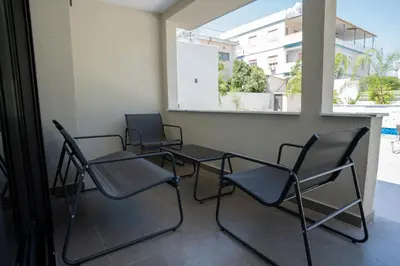 three chairs and a table in a room with a window at Raise Cityscape Limassol Suites in Limassol