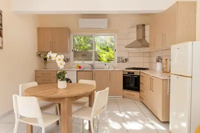 a kitchen with a wooden table and white chairs at 2 bedroom house near the beach in Limassol