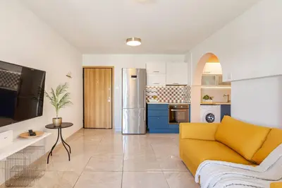 a living room with a yellow couch and a kitchen at Kastella Blue Apartment Near Beach in Larnaka