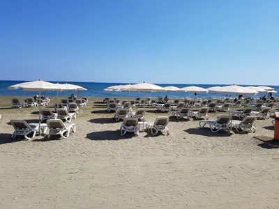 a bunch of chairs and umbrellas on a beach at Kastella Blue Apartment Near Beach in Larnaka