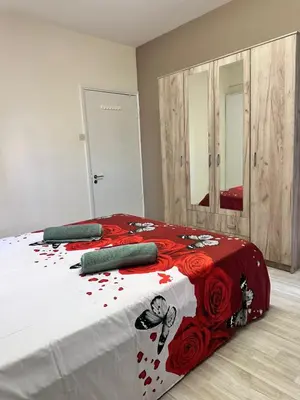 a bedroom with a bed with red flowers on it at Near Finikoudes Beach 15 in Larnaka