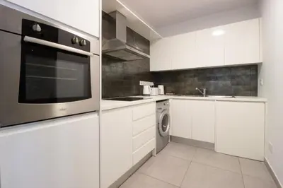 a kitchen with white cabinets and a washer and dryer at Modern City Retreat - Balcony and Chic Design in Nicosia