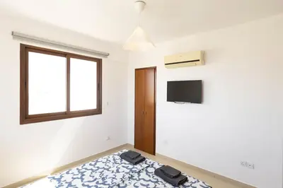 a bedroom with a bed and a window and a tv at Spacious & Bright Apartment with Balcony in Larnaka