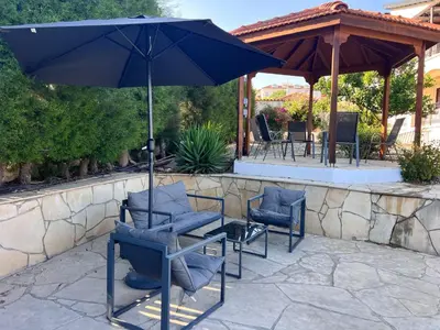 a group of chairs and an umbrella on a patio at Charming Erimi Villa with Private Pool and Garden View in Erimi