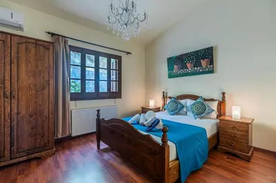 a bedroom with a bed and a chandelier at Villa Penelope Platres in Kato Platres