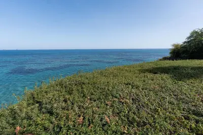 a grassy hill with the ocean in the background at Beachfront Mediterranean Escape 3bd Sea View Apartment in Pendakomo