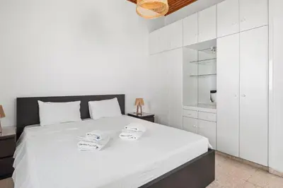 a white bedroom with a large bed with white cabinets at Shoreline Beach House in Larnaka