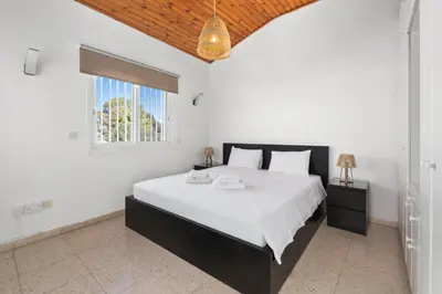 a bedroom with a large bed and a window at Shoreline Beach House in Larnaka