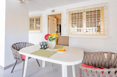 a white dining room table with chairs and a vase of flowers at Finikoudes gate in Larnaka