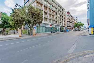 an empty street in a city with a building at Finikoudes gate in Larnaka