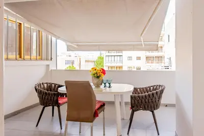 a white dining room with a white table and chairs at Finikoudes gate in Larnaka