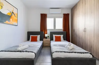 two beds in a room with orange pillows at Hilltop 2-Bedroom Apartment in Larnaka