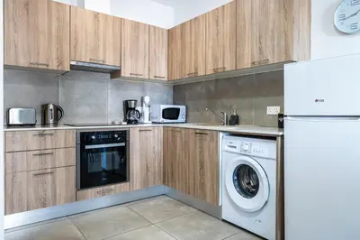 a kitchen with wooden cabinets and a washer and dryer at Hilltop 2-Bedroom Apartment in Larnaka