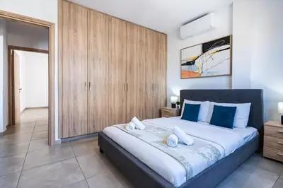 a bedroom with a large bed with blue pillows at Hilltop 2-Bedroom Apartment in Larnaka