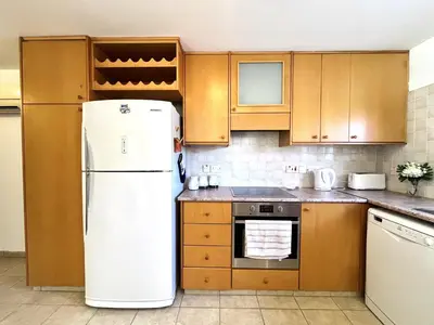 a kitchen with a white refrigerator and wooden cabinets at STAY Agapi Sea view Villa in Pissouri