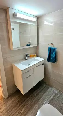 a bathroom with a sink and a mirror and a toilet at Dasoudi Pecora Beach Apartment in Limassol