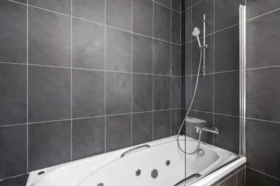 a bathroom with a bath tub with a shower at Parkside 2 Bedroom Apartment in Larnaka