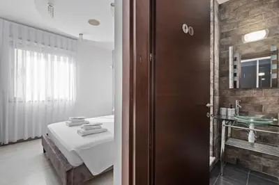 a room with a bed and a bathroom with a sink at Parkside 2 Bedroom Apartment in Larnaka