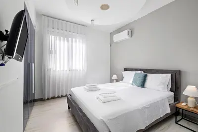 a white bedroom with a bed and a tv at Parkside 2 Bedroom Apartment in Larnaka