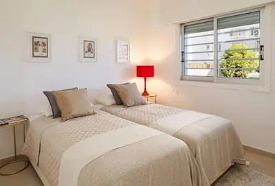 two beds in a white room with a window at Melon Boutique Seafront Apartment in Limassol