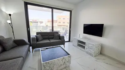 a living room with a flat screen tv and a couch and chair at Pool Citylux Apartment in Larnaka