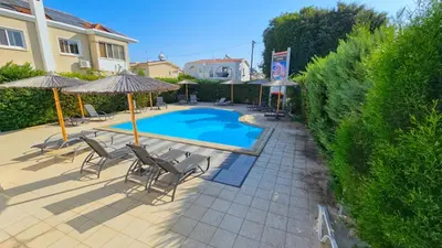 a swimming pool with lounge chairs and umbrellas at Pool Citylux Apartment in Larnaka
