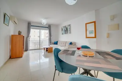 a living room with a dining room table and blue chairs at Cozy Mackenzie Getaway in Larnaka