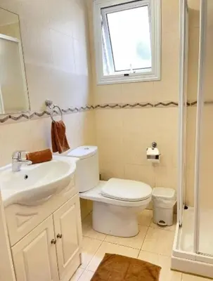 a bathroom with a toilet and a sink and a window at Villa Flamingo ,private pool & Sea view in Ayia Napa