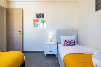 a bedroom with two beds with yellow sheets and a nightstand at Ondo 2-Bedroom Apartment in Larnaka