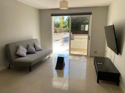 a living room with a couch and a tv at Nissi Bliss Apartment in Ayia Napa