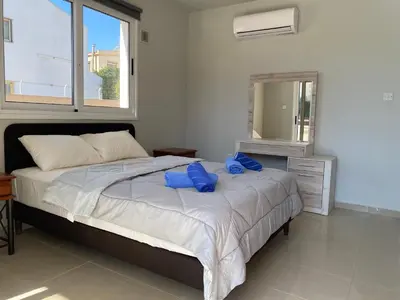 a bedroom with a large bed with blue bags on it at Nissi Bliss Apartment in Ayia Napa