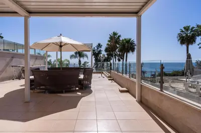 a patio with an umbrella and chairs and the ocean at Beachfront Luxury Living Limassol in Limassol