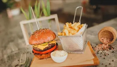 a hamburger and french fries on a wooden tray at THE PALMiA I iskele I Trikomo in Aglantzia