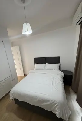 a bedroom with a white bed with a black headboard at Villa Keskin - Girne in Ayios Ioannis