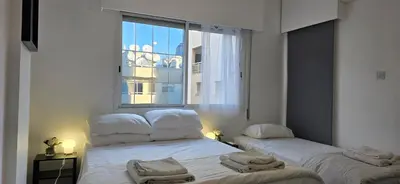two beds in a room with a large window at Executive 2BR Spacious Apartment , Limassol Center, 2 Balconies, Ideal Business Stay - SuperCentro! in Limassol